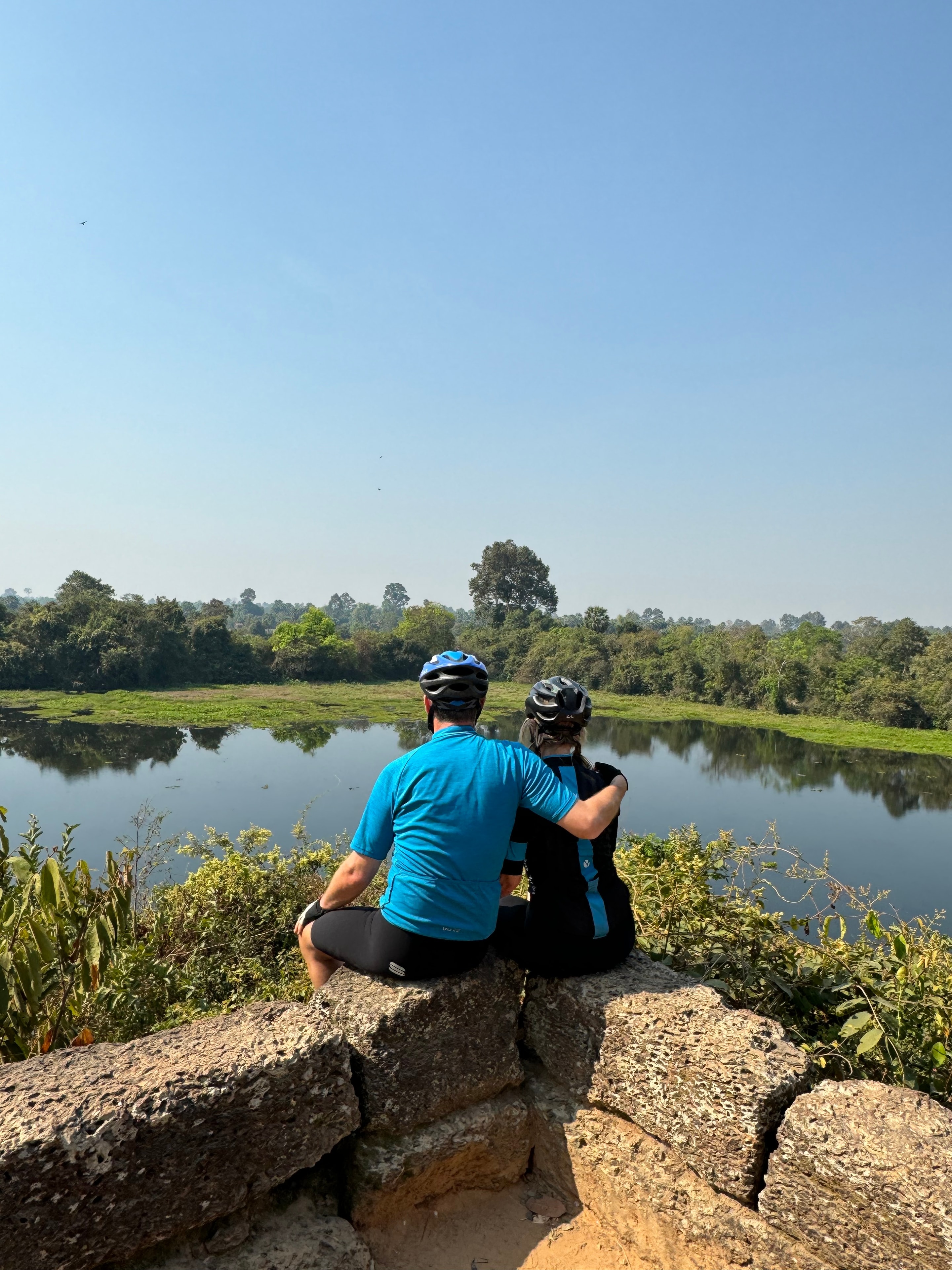 Ho Chi Minh to Angkor Wat — two cyclists resting overlooking a river landscape